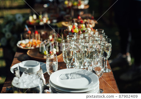 Table of various snacks, sandwiches, strawberries and champagne glasses. Buffet for wedding guests Table of various snacks, sandwiches, strawberries and champagne glasses. Buffet for wedding guests 87902409