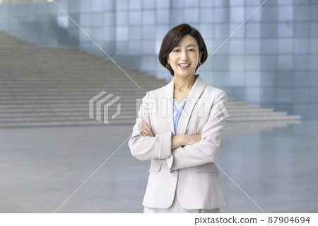 A business woman in her thirties smiling with her arms crossed looking at the camera 87904694