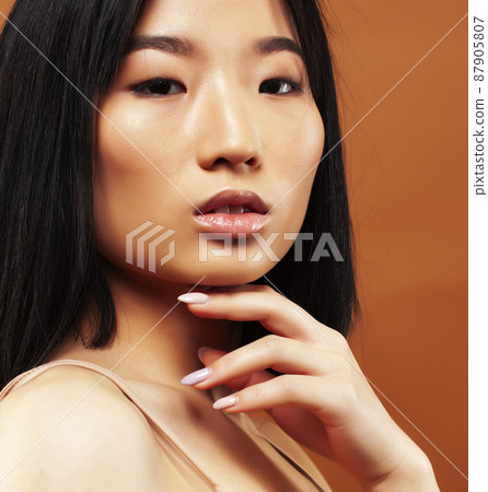 young pretty asian woman cheerful smiling posing on warm brown background, lifestyle people concept 87905807