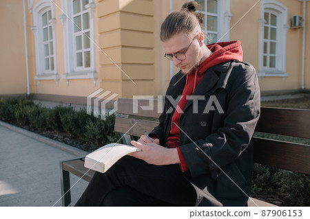 Boy sitting at the bench at the park and writing something 87906153