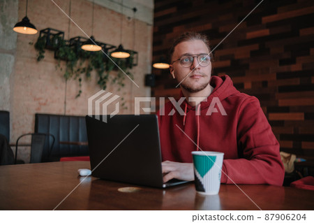 Portrait of happy male freelancer in optical eyewear for vision correction smiling at camera during break from web working online, cheerful hipster blogger sitting in cafe with mockup laptop 87906204
