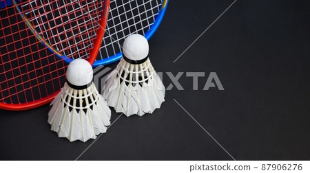 White cream badminton shuttlecocks, badminton rackets on black floor of indoor badminton court, soft and selective focus on shuttlecock, concept for badminton sport lovers around the world White cream badminton shuttlecocks, badminton rackets on black floor of indoor badminton court, soft and selective focus on shuttlecock, concept for badminton sport lovers around the world 87906276