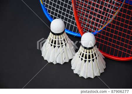 White cream badminton shuttlecocks, badminton rackets on black floor of indoor badminton court, soft and selective focus on shuttlecock, concept for badminton sport lovers around the world 87906277