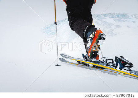 Close-up of freeride ski boots on snow. Skitour concept. Used worn boots on a male skier against the background of a glacier in cloudy weather in the mountains Close-up of freeride ski boots on snow. Skitour concept. Used worn boots on a male skier against the background of a glacier in cloudy weather in the mountains 87907012