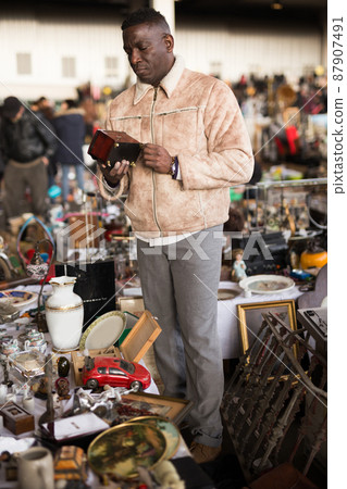 ordinary Afro-American guy considers things sacond hands on flea market 87907491