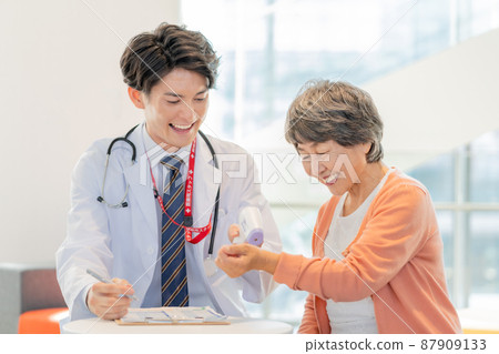 Young male doctor measuring the fever of senior women Photo cooperation "LINK FOREST] 87909133