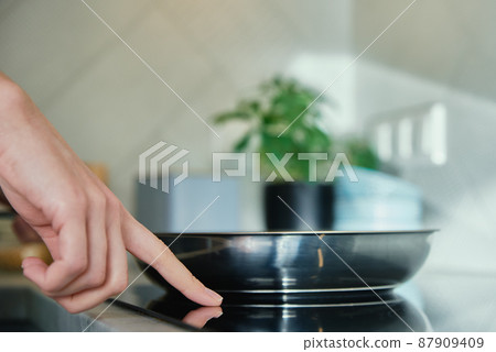 Frying pan on induction hob at kitchen 87909409