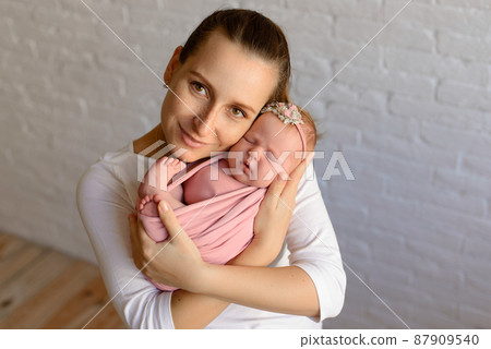 Loving mom carying of her newborn baby at home Loving mom carying of her newborn baby at home 87909540