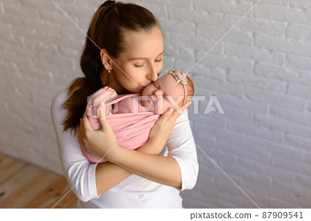 Loving mom carying of her newborn baby at home 87909541