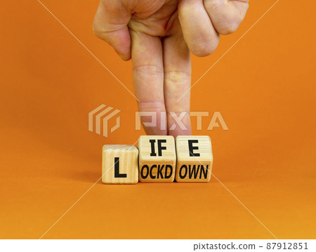 Life with lockdown symbol. Doctor turns wooden cubes and changes words 'lockdown' to'life'. Beautiful orange background. Covid-19 pandemic and life with lockdown concept. Copy space. 87912851
