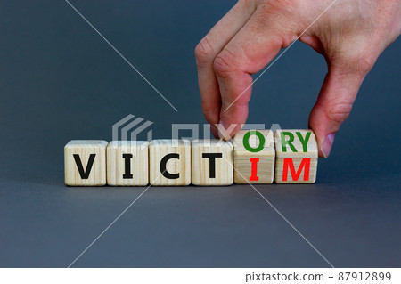 From victim to victory symbol. Businessman turns wooden cubes and changes concept words Victim to Victory. Beautiful grey background. Business support from victim to victory concept. Copy space. 87912899