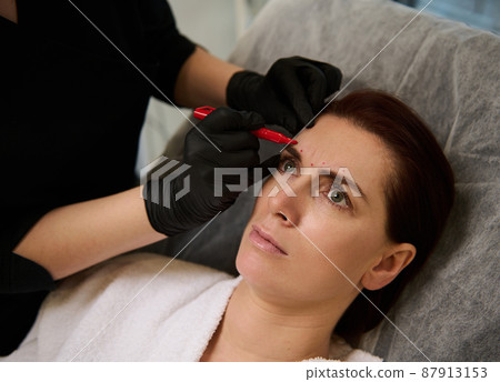 Aesthetician beautician drawing guidelines for cosmetic product injection. Thread facelift with arrows for middle aged woman skin, facial contouring procedure with meso threads for facial rejuvenation 87913153