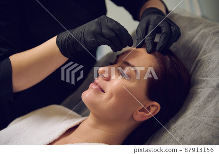 Close-uo of a happy middle aged beautiful woman taking care of her face skin in modern wellness spa salon. Anti-aging anti wrinkles and rejuvenationg beauty treatment. Health care and medicine Close-uo of a happy middle aged beautiful woman taking care of her face skin in modern wellness spa salon. Anti-aging anti wrinkles and rejuvenationg beauty treatment. Health care and medicine 87913156