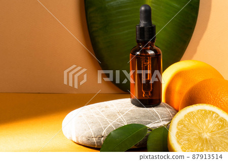 Vitamin C serum in a glass bottle, orange background. Organic SPA cosmetics with orange oil. Pipette with cosmetic orange oil on the orange bubble. Natural cosmetics. Vitamin C. Vitamin C serum in a glass bottle, orange background. Organic SPA cosmetics with orange oil. Pipette with cosmetic orange oil on the orange bubble. Natural cosmetics. Vitamin C. 87913514