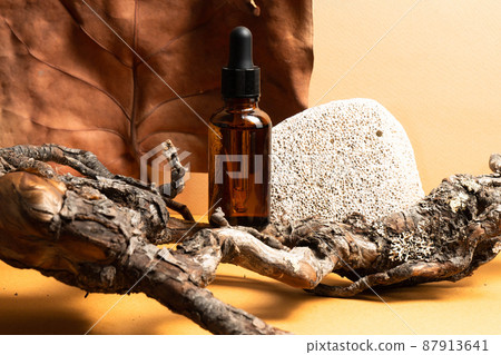 One bottle of oil and serum on a yellow background with a decor of driftwood and shells. Space for copying. The concept of an advertising template for cosmetics. 87913641