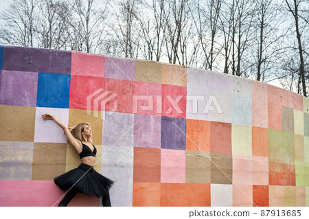 Blonde ballet dancer posing next to colorful wall 87913685