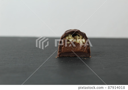 incision chocolate case candy stuffed with chocolate pralines and crushed peanuts close-up on a gray background with space for copyspace text. Chocolate Day Sweet Homemade Desserts incision chocolate case candy stuffed with chocolate pralines and crushed peanuts close-up on a gray background with space for copyspace text. Chocolate Day Sweet Homemade Desserts 87914018