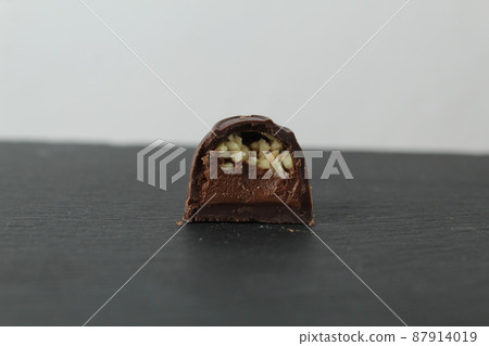 incision chocolate case candy stuffed with chocolate pralines and crushed peanuts close-up on a gray background with space for copyspace text. Chocolate Day Sweet Homemade Desserts incision chocolate case candy stuffed with chocolate pralines and crushed peanuts close-up on a gray background with space for copyspace text. Chocolate Day Sweet Homemade Desserts 87914019