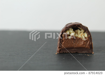 incision chocolate case candy stuffed with chocolate pralines and crushed peanuts close-up on a gray background with space for copyspace text. Chocolate Day Sweet Homemade Desserts incision chocolate case candy stuffed with chocolate pralines and crushed peanuts close-up on a gray background with space for copyspace text. Chocolate Day Sweet Homemade Desserts 87914020