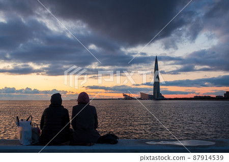 Two girls on the promenade admire the sunset over the sea. 87914539