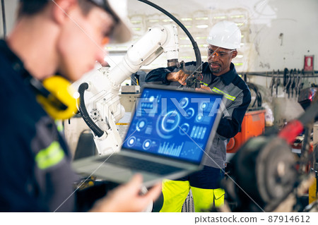 Young factory worker working with adept robotic arm 87914612