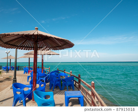 Beach cafe with plastic furniture, wood parasols Beach cafe with plastic furniture, wood parasols 87915018