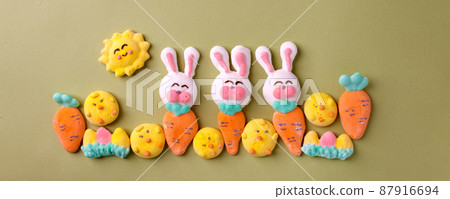Happy Easter concept. Preparation for holiday. Easter marshmallow candy chiken, rabbit, carrot, bunny on green pastel background. Simple cute, funny minimalism flat lay top view, copyspace banner 87916694