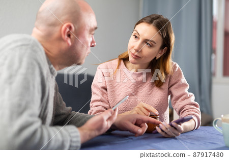 Wife and husband with smartphones having conversation 87917480