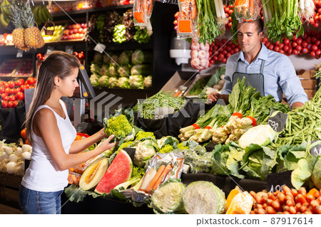 Woman customer choosing greens on market Woman customer choosing greens on market 87917614