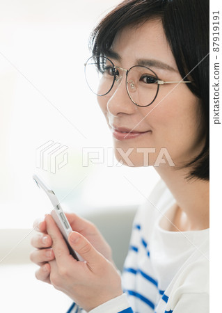 A woman wearing glasses and looking at a smartphone A woman wearing glasses and looking at a smartphone 87919191