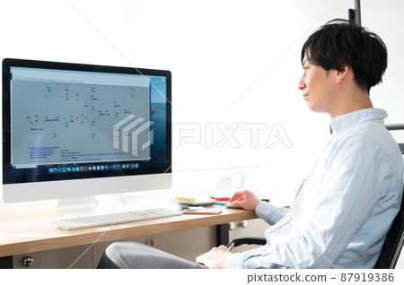 Male electrical engineer sitting in front of a computer Male electrical engineer sitting in front of a computer 87919386