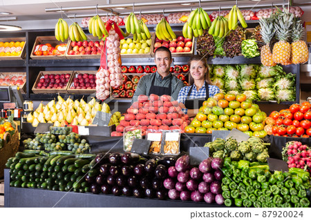 Man and woman sellers standing near vegetables and fruits 87920024