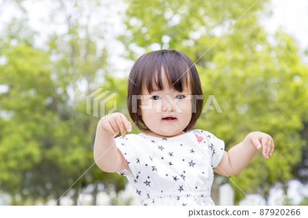 A little girl dancing with a smile against the backdrop of fresh green trees. Childcare, education, discipline, affection, happy image 87920266
