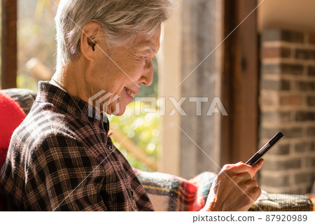 Profile of a senior woman who smiles when she sees her mobile phone Profile of a senior woman who smiles when she sees her mobile phone 87920989