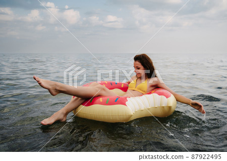 slender girl swims on an inflatable circle in the sea in summer slender girl swims on an inflatable circle in the sea in summer 87922495