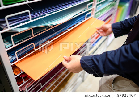 Male hand choosing orange paper in stationery shop Male hand choosing orange paper in stationery shop 87923467