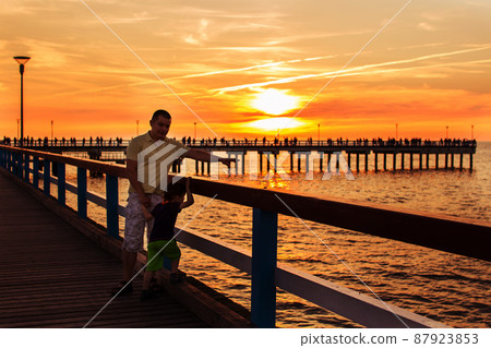 pier on the sea. sunset. Palanga. father and son walking along the waterfront pier on the sea. sunset. Palanga. father and son walking along the waterfront 87923853
