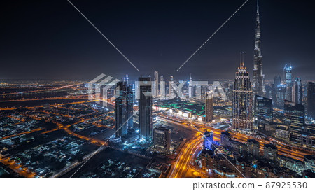 Panorama showing aerial view of tallest towers in Dubai Downtown skyline and highway night timelapse. 87925530