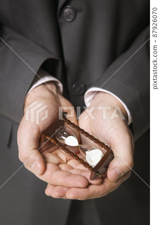 Businessman with hourglass in hands 87926070