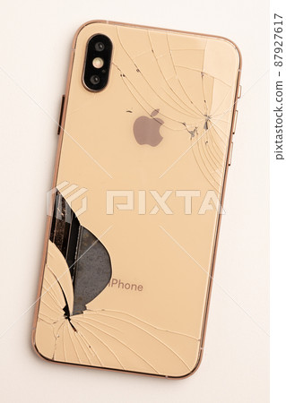 Top view the back of smartphone iPhone 11 with a broken glass and a damaged curved body close-up Top view the back of smartphone iPhone 11 with a broken glass and a damaged curved body close-up 87927617