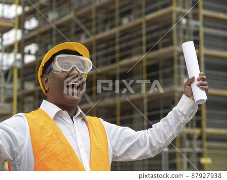 Hurrah, exulting and joyful Indian engineer holding rolled up plans on construction site Hurrah, exulting and joyful Indian engineer holding rolled up plans on construction site 87927938