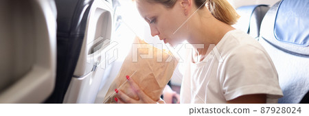 Young woman flying in airplane and breathing into paper bag Young woman flying in airplane and breathing into paper bag 87928024