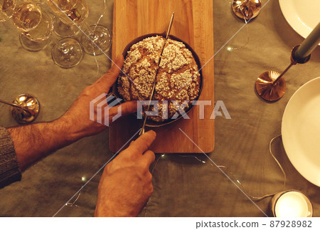 Man cutting delicious freshly baked homemade pie cake or xmas cupcake with knife on rustic table 87928982