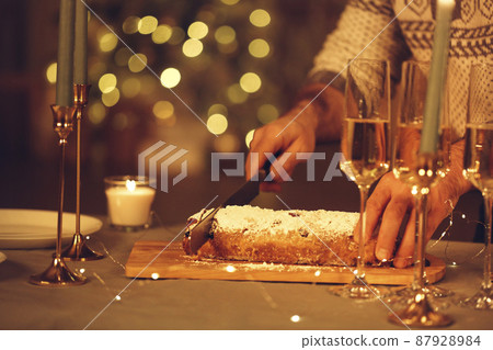Woman cutting freshly baked homemade pie with knife, celebrating Christmas Eve with friends at home. Woman cutting freshly baked homemade pie with knife, celebrating Christmas Eve with friends at home. 87928984