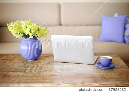 Open laptop, cup of coffee and vase with yellow flowers on retro wood textured table in living room Open laptop, cup of coffee and vase with yellow flowers on retro wood textured table in living room 87928985