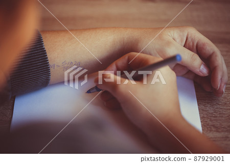 Student cheating during exam in university, reading cheat sheet with formula written on hand Student cheating during exam in university, reading cheat sheet with formula written on hand 87929001