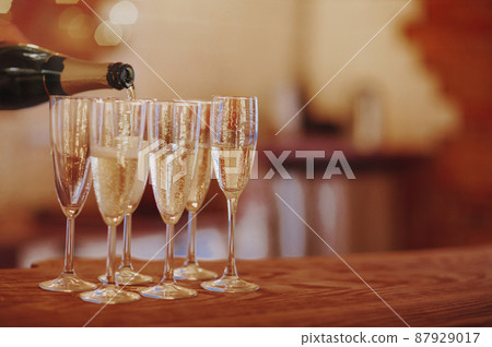 Unrecognizable male filling wineglass with champagne while standing on banquet tabl 87929017