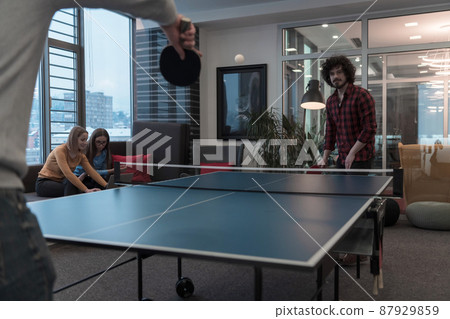 Two young start up business man playing ping pong tennis at modern creative office space people group have meeting and brainstorming in background 87929859