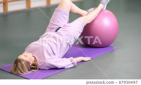 woman doing bridge using fitball in a fitness club. pilates workout exercise. real people woman doing bridge using fitball in a fitness club. pilates workout exercise. real people 87930497