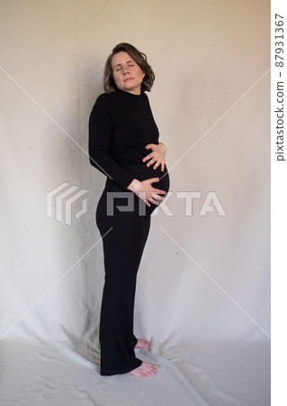 Pregnant caucasian smiling woman posing in studio Pregnant caucasian smiling woman posing in studio 87931367